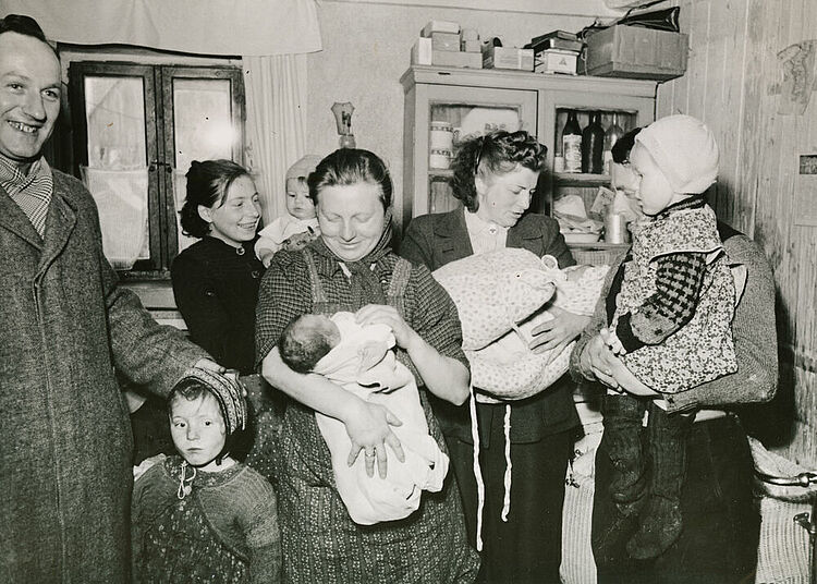 Nachkriegszeit in Deutschland: Mütter und Kleinkinder in Ansbach, nachdem sie Kleidung und Lebensmittel aus Schweden empfangen haben, um 1950